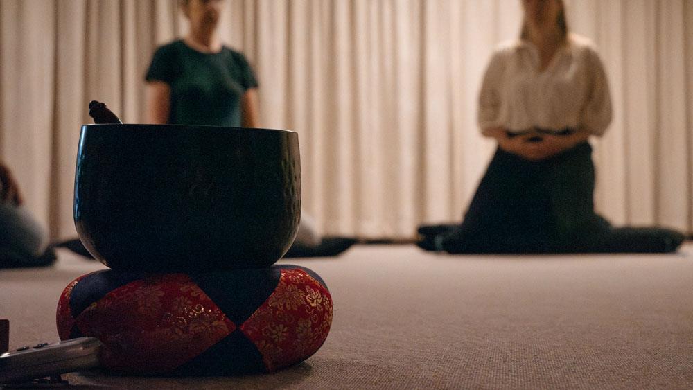 een meditatiebel op een kussentje op de grond in de zendo tijdens de les